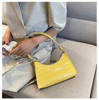 Frau mit gelber Croco-Lederhandtasche auf Sofa, elegantes Design, modisches Accessoire.