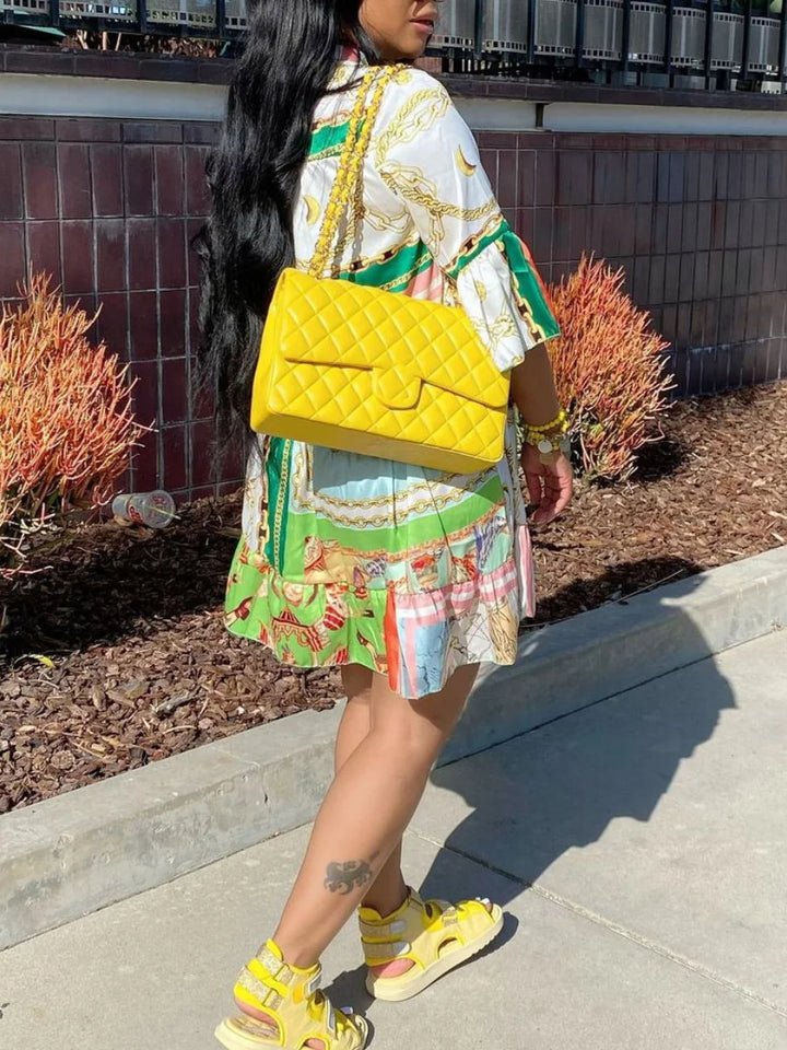 Frau mit gelber Designer-Handtasche, Sommerkleid und Sandalen, modisch, urbaner Stil.