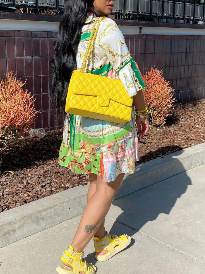 Frau mit gelber Designer-Handtasche, Sommerkleid und Sandalen, modisch, urbaner Stil.