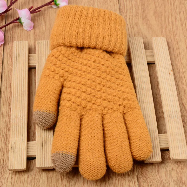 Gelbe gestrickte Handschuhe mit braunen Fingerspitzen auf Holzuntergrund, Wintermode Accessoire.