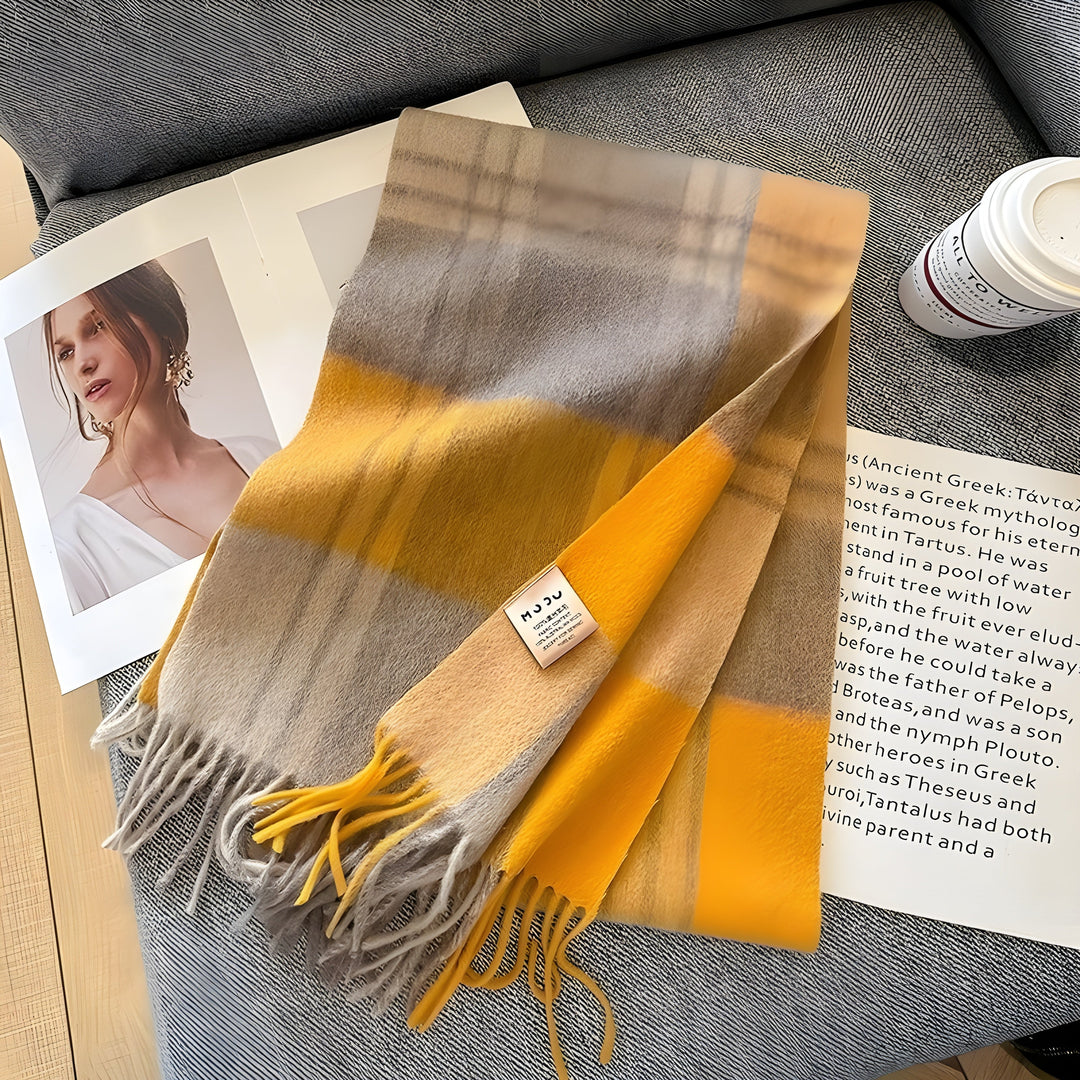 Gelber karierten Schal aus Wolle auf grauem Sofa, Modezeitschrift und Kaffeetasse daneben.