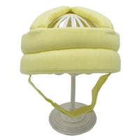 Gelber Baby-Schutzhelm aus Baumwolle auf weißem Ständer, ideal für Kleinkind-Sicherheit.