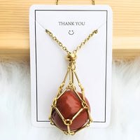 Goldene Halskette mit rotem Edelsteinanhänger auf weißem Hintergrund, Schmuckdesign.