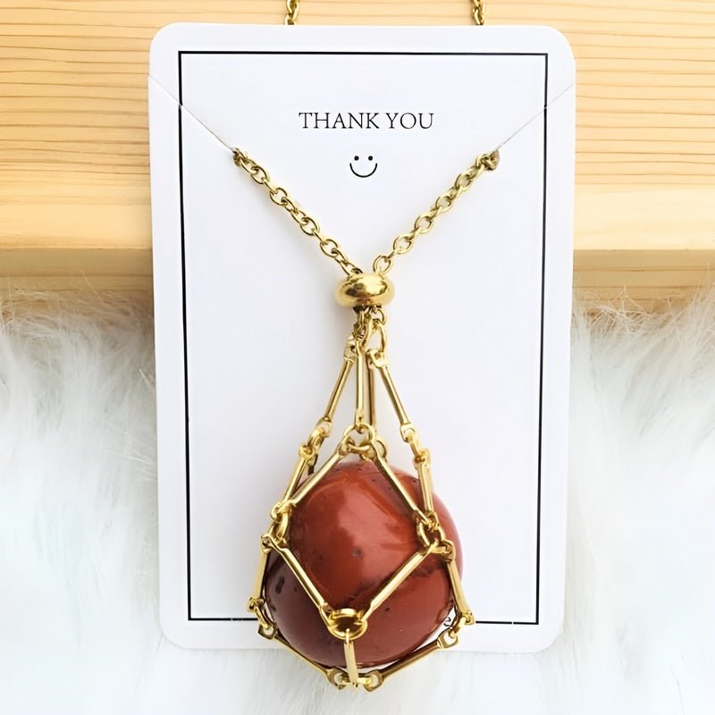 Goldene Halskette mit rotem Edelsteinanhänger auf weißem Hintergrund, Schmuckdesign.