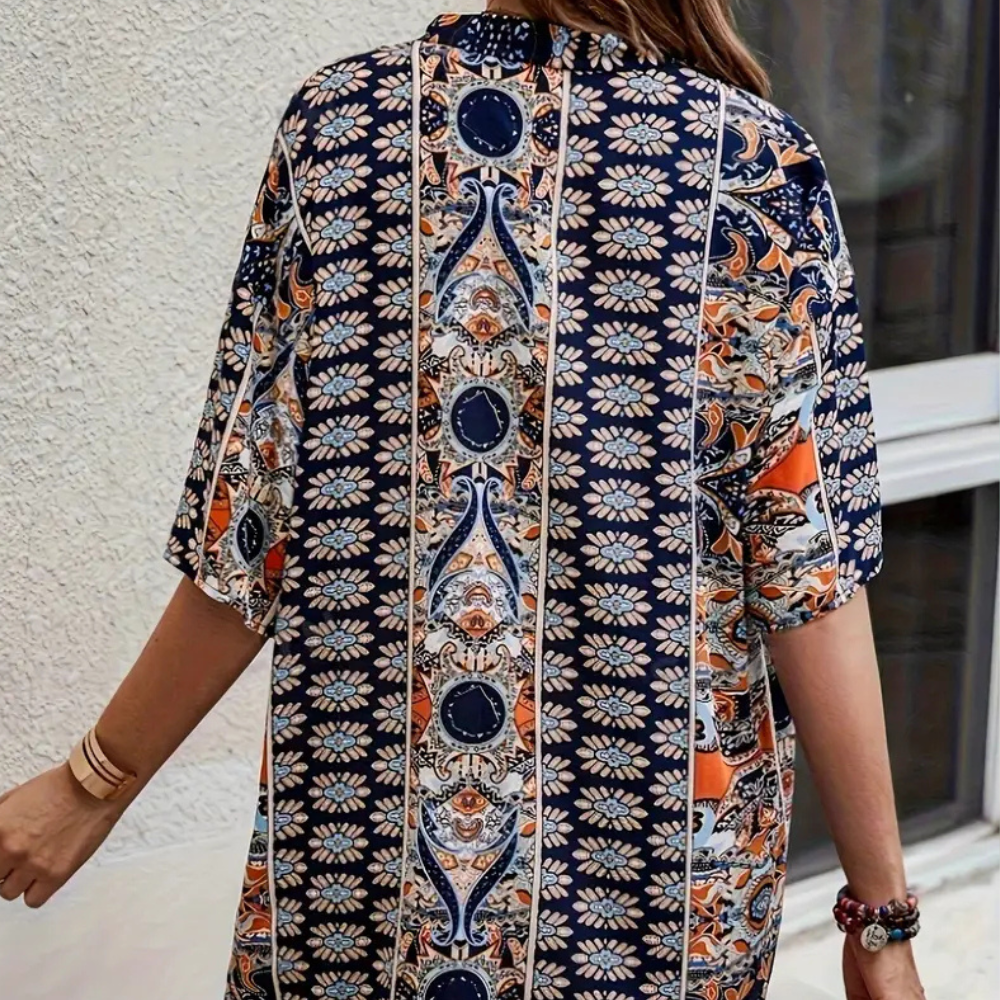 Frau in bunter, gemusterter Kimono-Jacke aus Baumwolle vor weißer Wand.