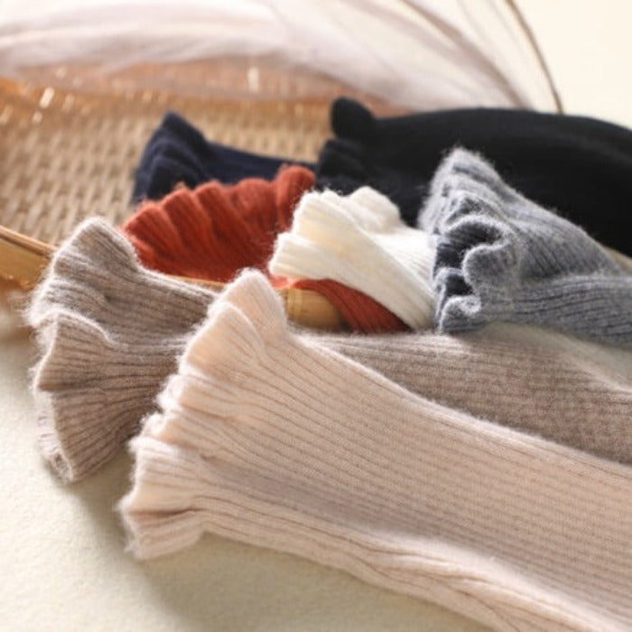 Mehrfarbige, gerippte Strickstulpen aus Wolle auf Korb, Herbstmode Accessoire.