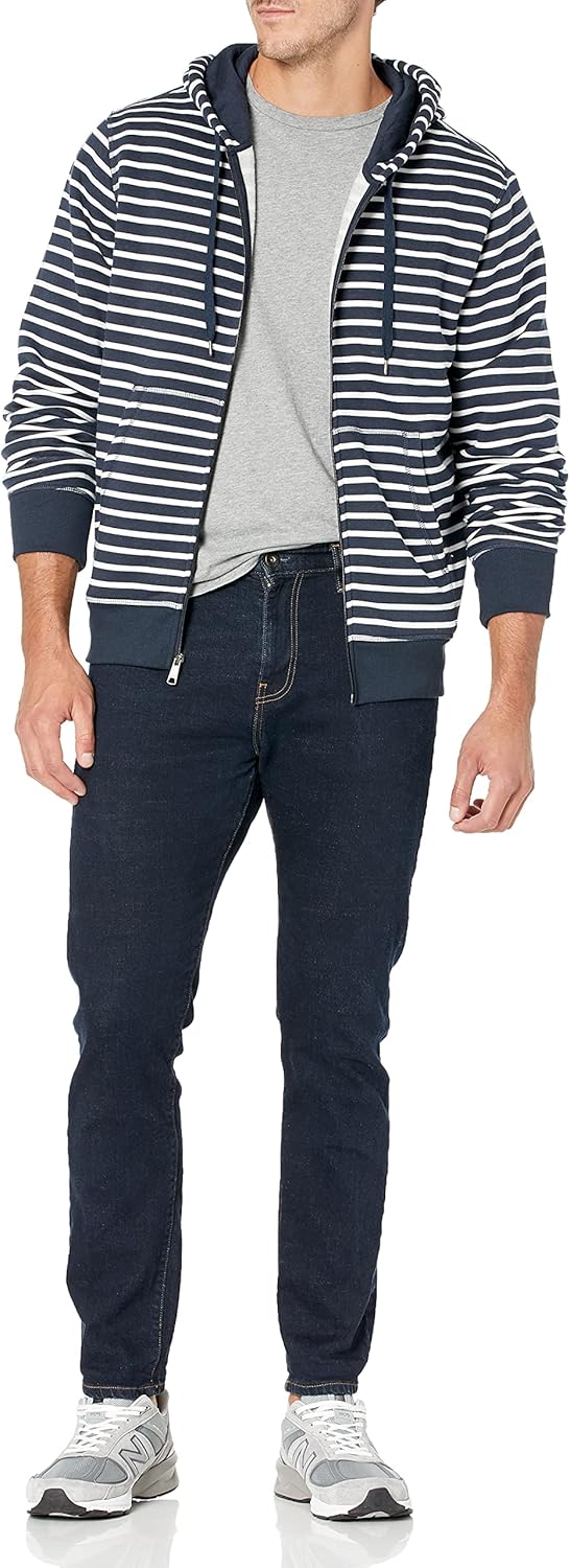 Mann in gestreifter Kapuzenjacke, grauem T-Shirt, dunklen Jeans und Sneakers.