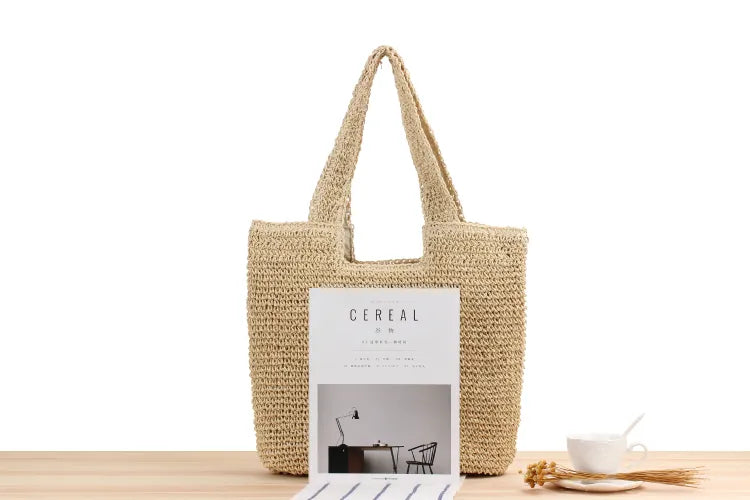 Beige Strohtasche mit Zeitschrift auf Holztisch, nachhaltige Mode, umweltfreundlich, Sommeraccessoire.
