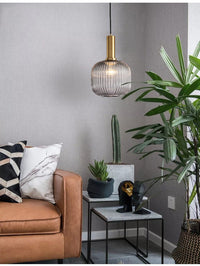 Braune Glas-Hängelampe im skandinavischen Stil über modernem Wohnzimmer mit Pflanzen und Sofa.