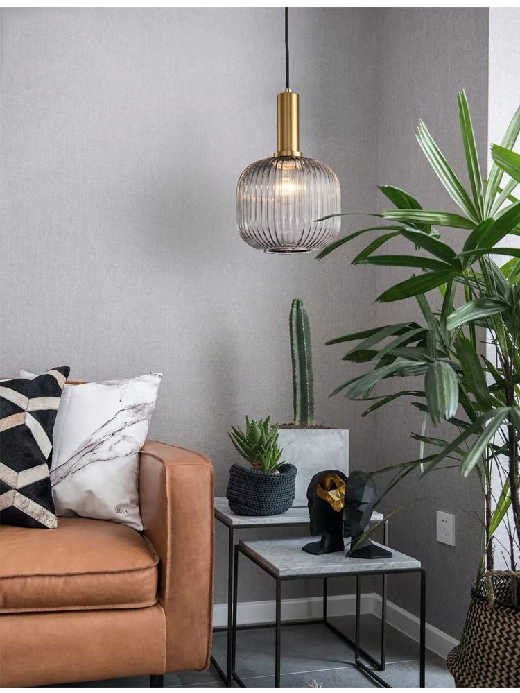 Braune Glas-Hängelampe im skandinavischen Stil über modernem Wohnzimmer mit Pflanzen und Sofa.