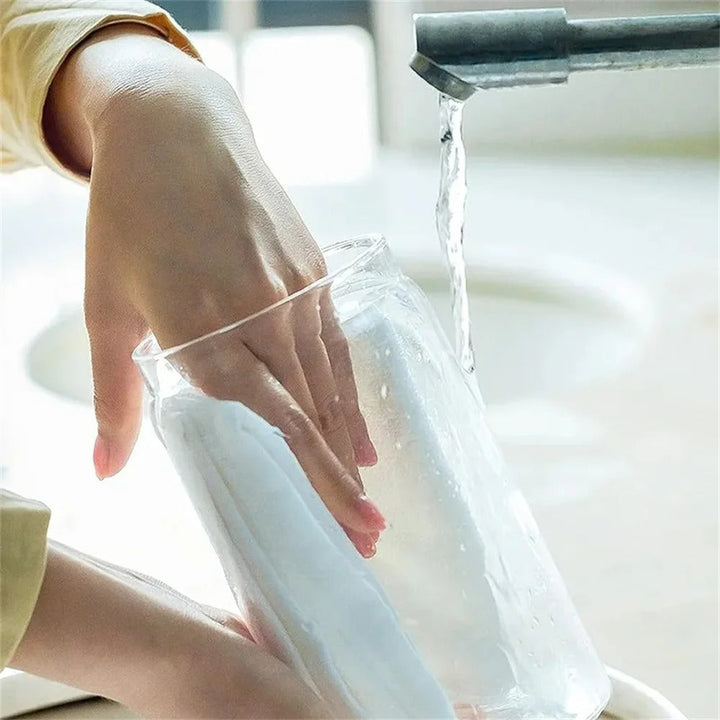 Hand reinigt Glas mit weißem Schwamm unter fließendem Wasser, Küchenreinigung, Hygiene.