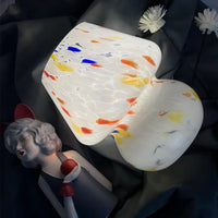 Weiße Glaslampe mit bunten Sprenkeln, dekorative Beleuchtung, modernes Design.