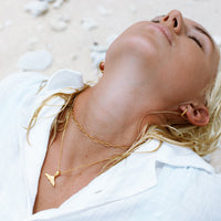 Frau mit goldener Walflossen-Halskette, Strand, Schmuck, Mode, Accessoire, elegantes Design.