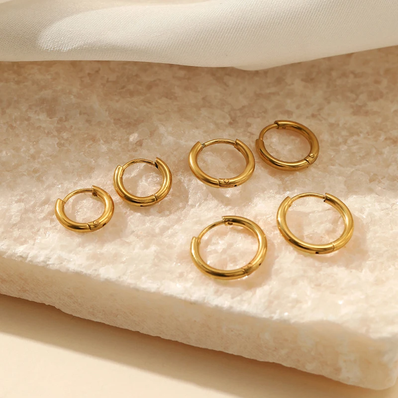 Goldene Creolen-Ohrringe auf Marmor, eleganter Schmuck, modische Accessoires, Damenmode.