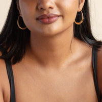 Frau mit goldenen Creolen, schwarzes Top, Nahaufnahme, Schmuck, Modeaccessoire, elegant.