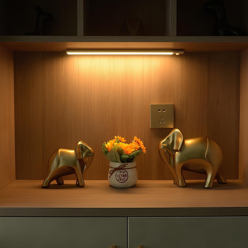 Goldene Elefantenfiguren und Blumen in Vase auf Holzregal, LED-Beleuchtung, moderne Dekoration.