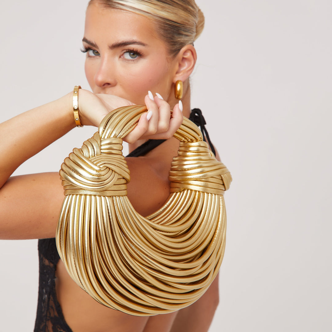 Frau mit goldener, geknüpfter Schultertasche, modisches Accessoire, elegantes Design.