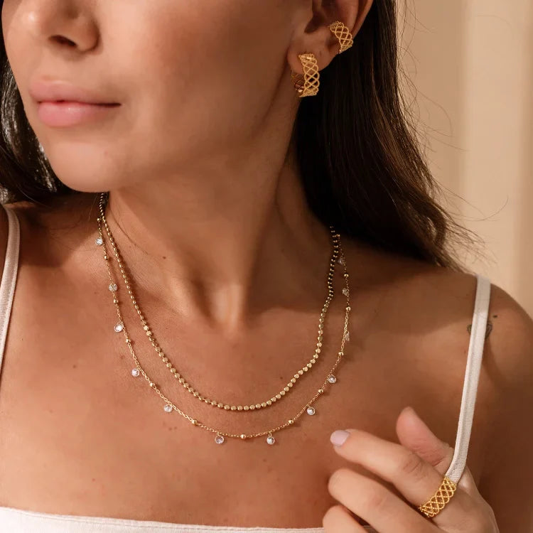 Frau mit goldener Halskette, Ohrringen und Ring, eleganter Schmuck, Nahaufnahme.