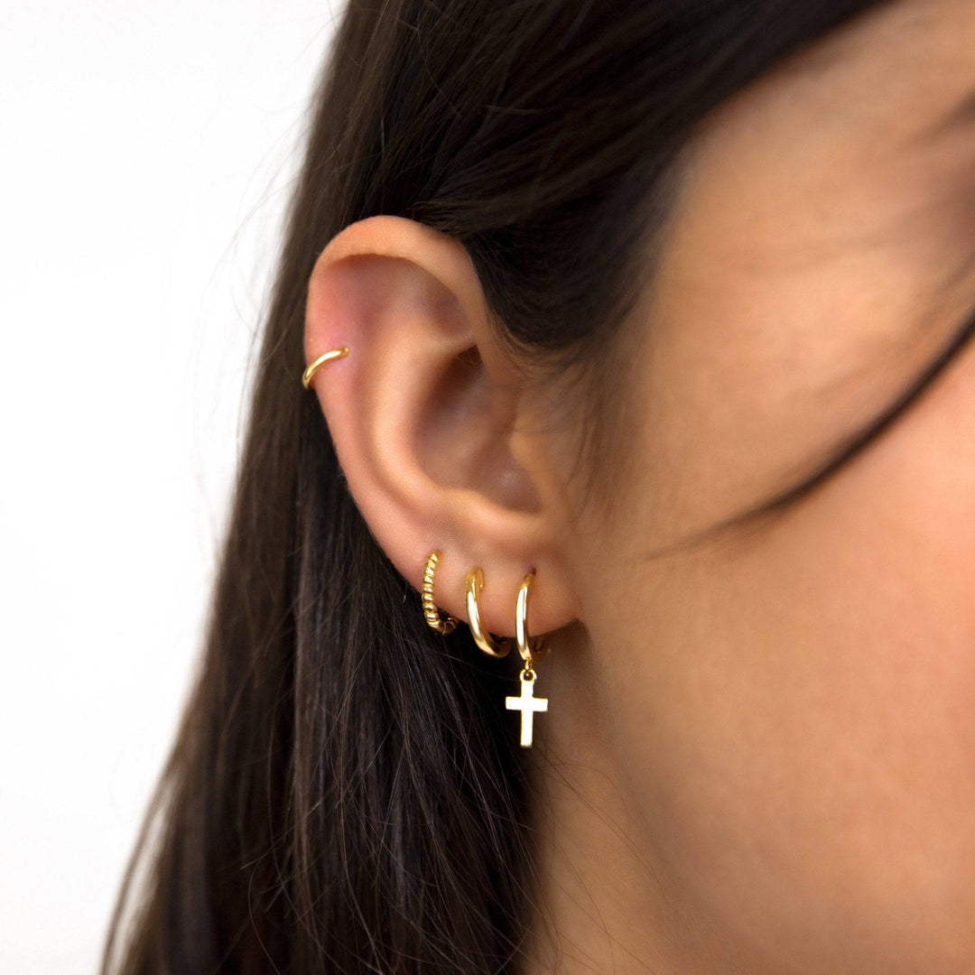 Frau mit goldenen Creolen und Kreuzanhänger, Ohrschmuck, modische Accessoires, Nahaufnahme.