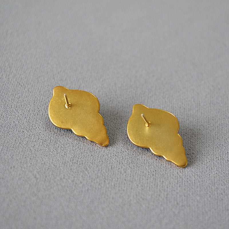 Goldene Muschel-Ohrringe auf grauem Hintergrund, eleganter Schmuck, maritimes Design.