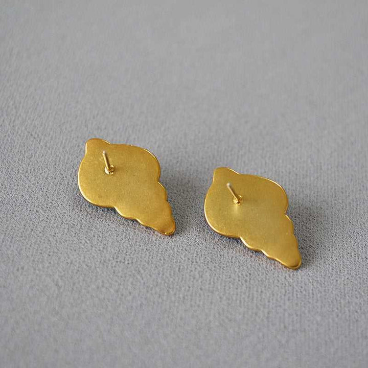 Goldene Muschel-Ohrringe auf grauem Hintergrund, eleganter Schmuck, maritimes Design.