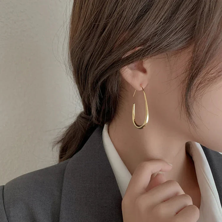 Frau mit goldenen Creolen-Ohrringen, elegantes Schmuckdesign, modisches Accessoire.