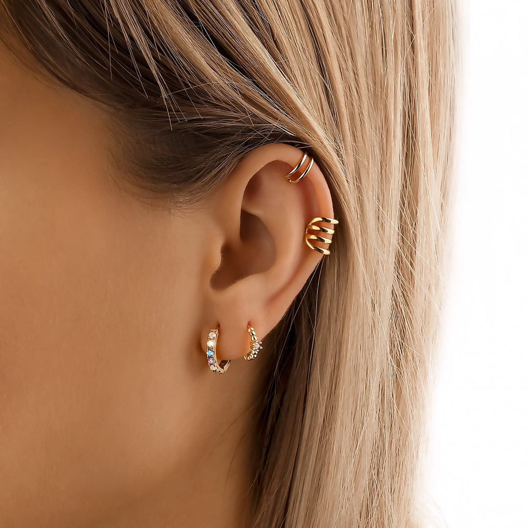 Frau mit goldenen Ohrringen, Creolen und Ohrmanschetten, modischer Schmuck, Nahaufnahme.