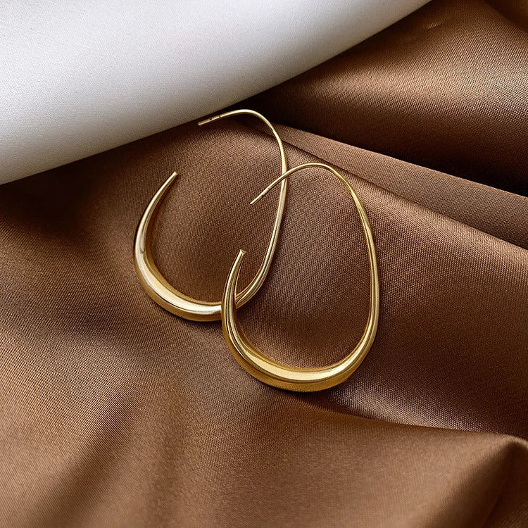 Goldene Ohrringe auf braunem Satin, elegantes Schmuckdesign, modische Accessoires.