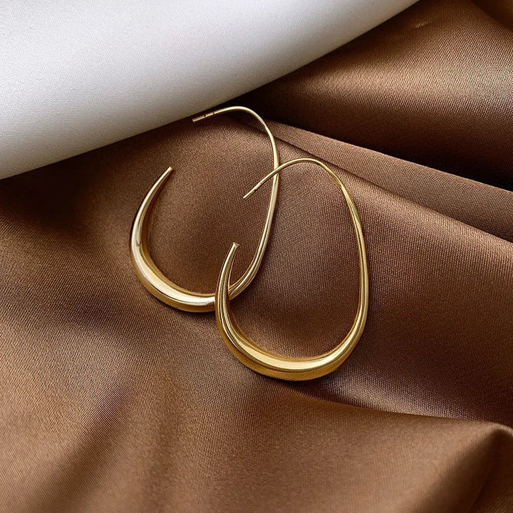 Goldene Ohrringe auf braunem Satin, elegantes Schmuckdesign, modische Accessoires.