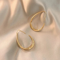 Goldene Creolen Ohrringe auf beigem Satin, eleganter Schmuck, modisches Accessoire.