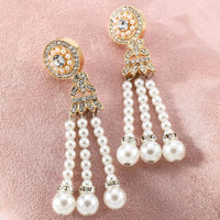 Goldene Ohrringe mit Perlen und Strasssteinen auf rosa Hintergrund, eleganter Schmuck.