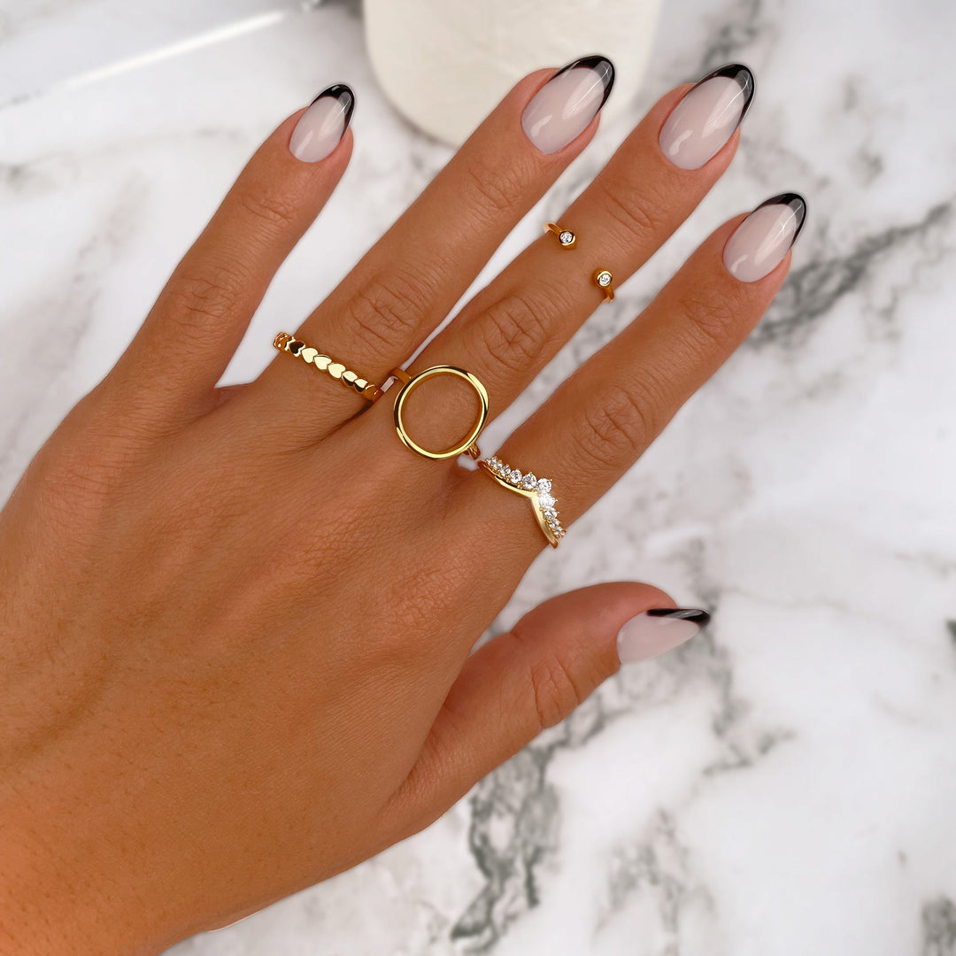 Hand mit goldenen Ringen und Nageldesign auf Marmortisch, Schmuck, Modeaccessoires.