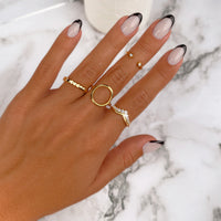 Hand mit goldenen Ringen und Nageldesign auf Marmortisch, Schmuck, Modeaccessoires.