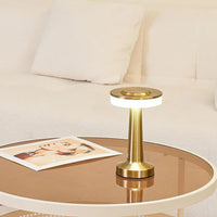 Goldene LED-Tischlampe auf Glastisch vor beigem Sofa, modernes Design, Wohnzimmerbeleuchtung.