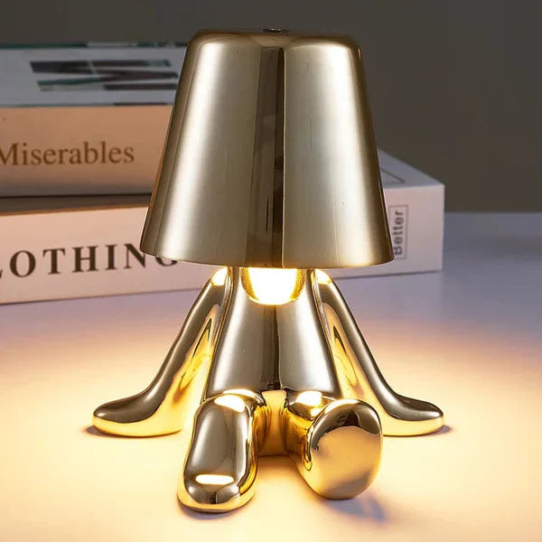 Goldene Tischlampe in Form einer sitzenden Figur, modernes Design, warmes Licht, Dekoration.