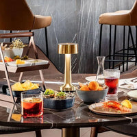 Goldene LED-Tischlampe auf Marmortisch mit Snacks und Getränken in modernem Restaurant.