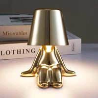 Goldene Tischlampe in Form einer sitzenden Figur, modernes Design, ideal für Wohnzimmer-Dekor.