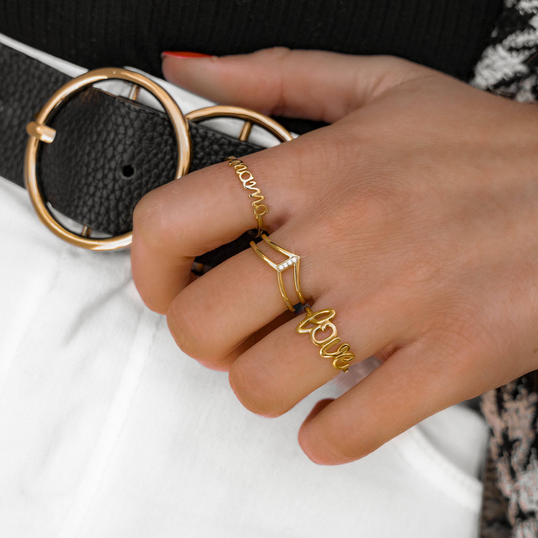 Goldene Ringe "Mama" und "Love" auf Hand, modischer Schmuck, Damenaccessoire, Nahaufnahme.