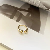 Goldener offener Ring auf Buchseite, minimalistisches Design, Schmuck, Modeaccessoire.