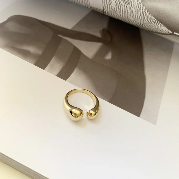 Goldener offener Ring auf Buchseite, minimalistisches Design, Schmuck, Modeaccessoire.
