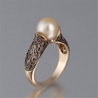 Goldener Ring mit Perle und filigranem Muster, eleganter Schmuck, luxuriöses Design.