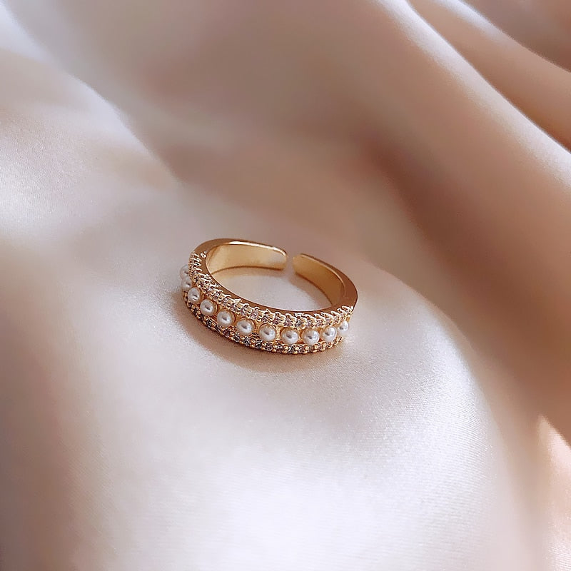 Goldener verstellbarer Ring mit Perlen auf Seidenstoff, eleganter Schmuck, modisches Accessoire.