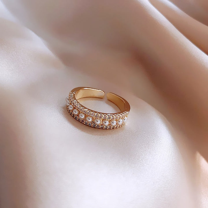 Goldener verstellbarer Ring mit Perlen auf Seidenstoff, eleganter Schmuck, modisches Accessoire.