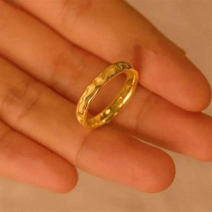 Goldener Ring auf Handfläche, gehämmertes Design, Schmuck, Damenring, modisch, elegant.