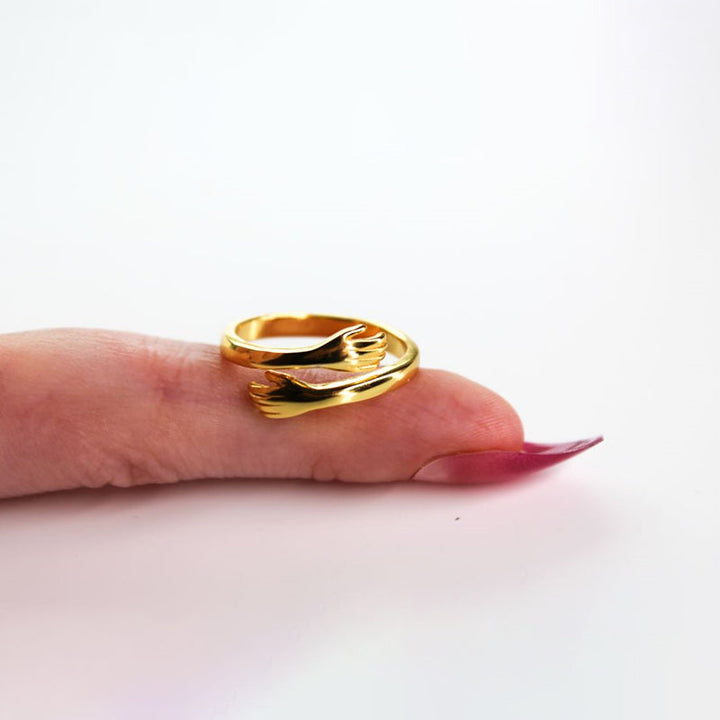Goldener Umarmungsring auf Finger, elegantes Schmuckdesign, modischer Damenring.
