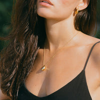 Frau mit goldener Tropfen-Halskette und Ohrringen, eleganter Schmuck, Nahaufnahme.