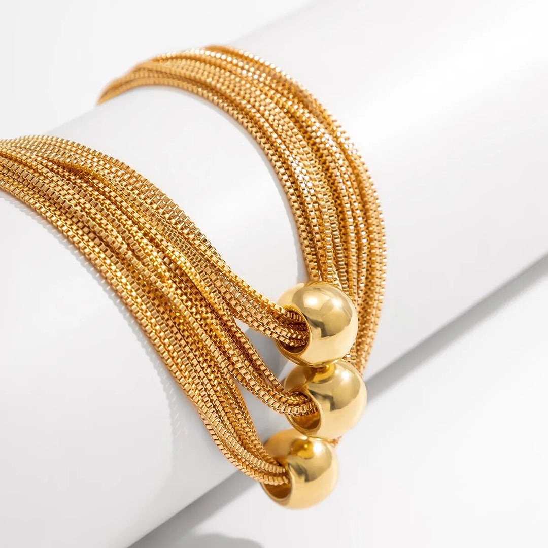 Goldenes Armband mit Kugelakzenten, mehrsträngig, elegantes Schmuckdesign, Damenaccessoire.