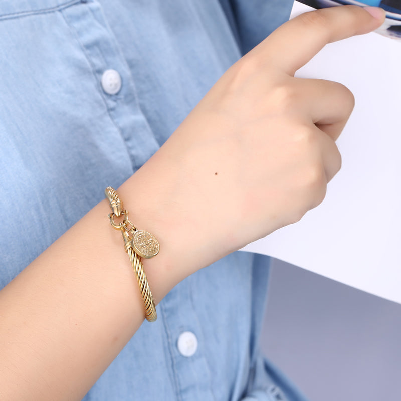 Goldenes Armband mit Münzanhänger, Damenmode, elegantes Schmuckdesign, Nahaufnahme.