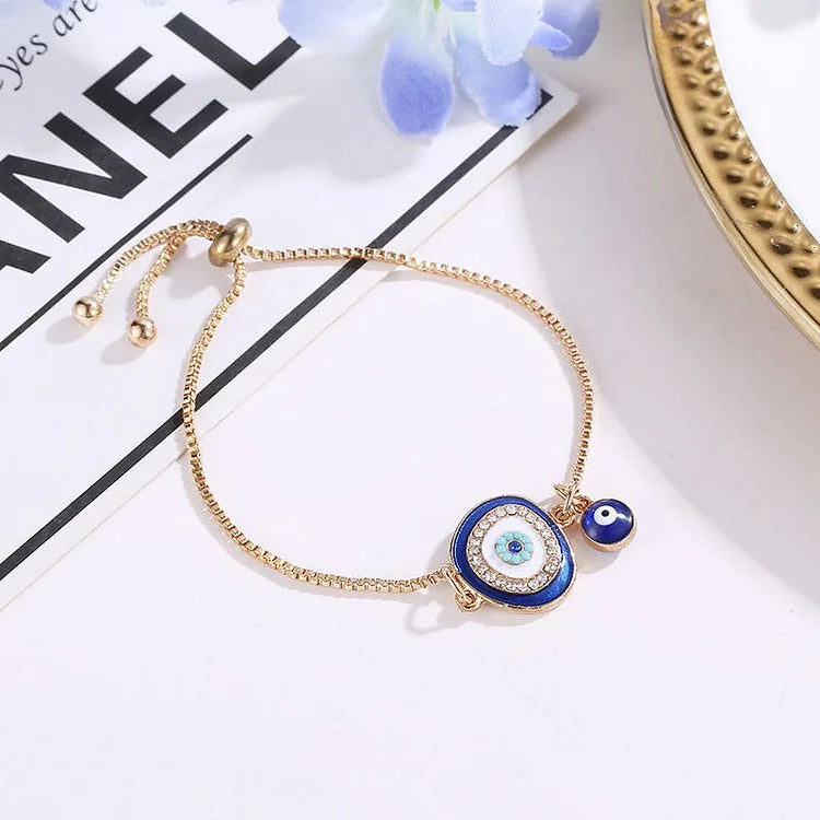 Goldenes Armband mit blauem Nazar-Amulett, verstellbar, auf weißem Hintergrund.