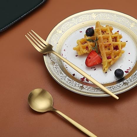 Goldenes Besteck-Set auf Teller mit Waffeln, Erdbeeren und Blaubeeren, luxuriöses Essgeschirr.